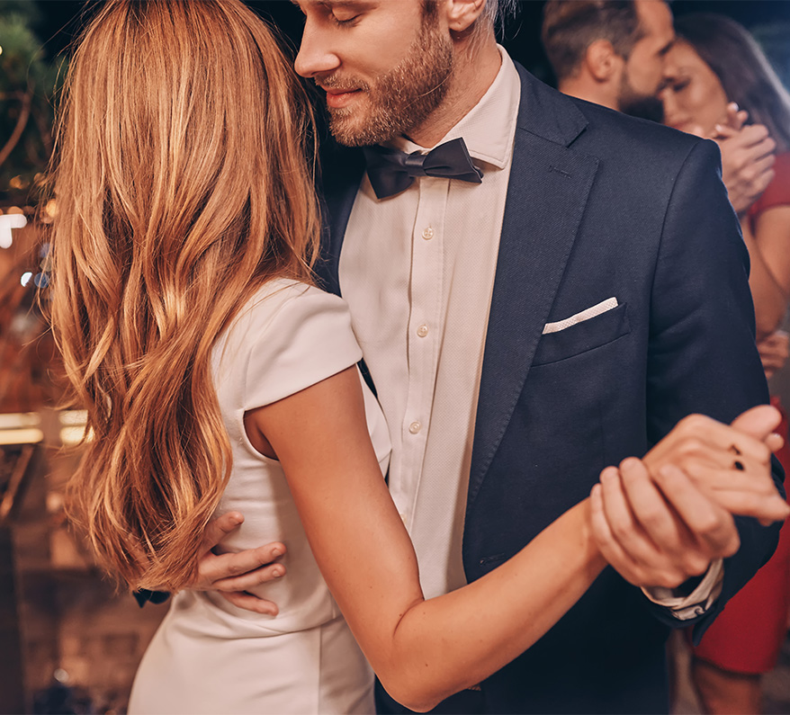 a man in a blue suit and blonde woman in a white dress dancing
