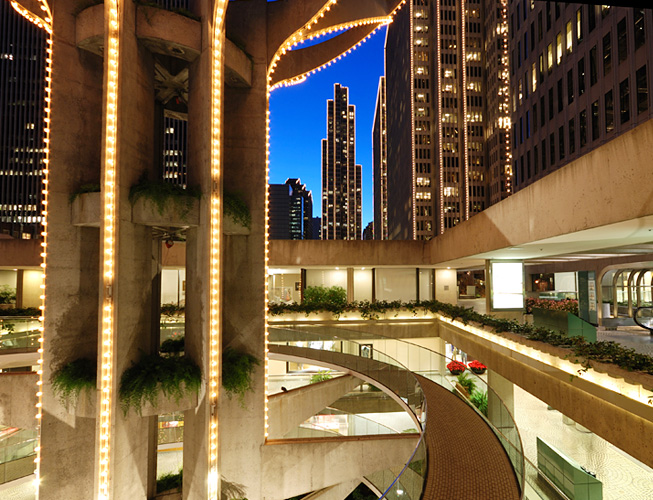 A lit-up exterior view of a building with a city skyline in the background