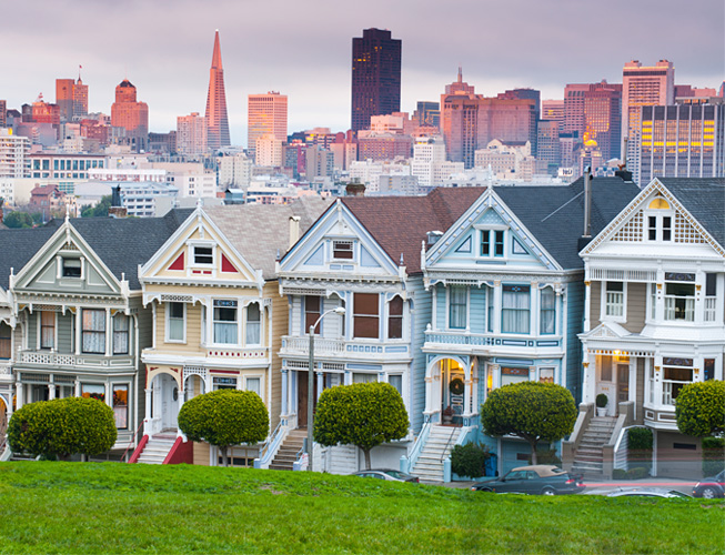 a row of colorful houses with a city skyline in the background