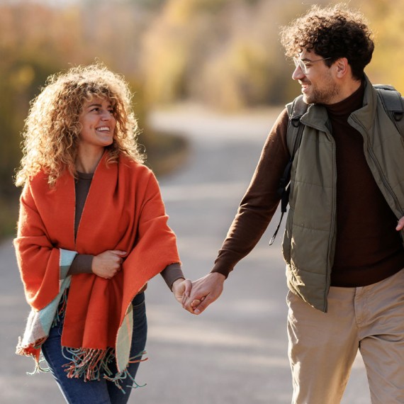 a man and woman holding hands and walking on a road