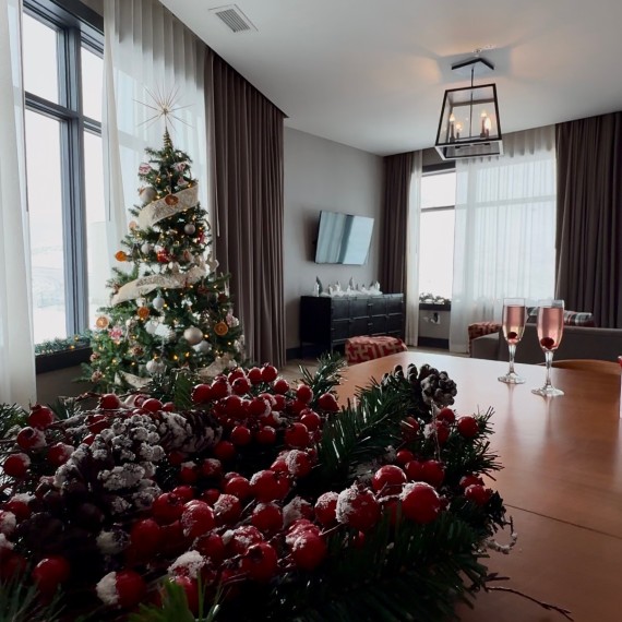 a christmas tree in a room with a table and a glass of wine