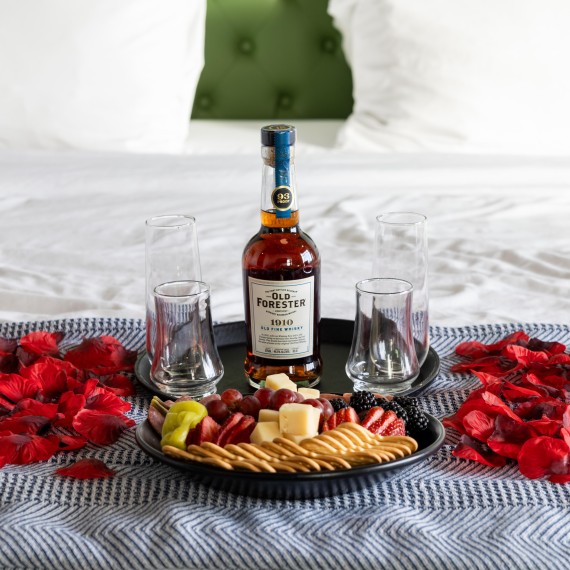 a plate of food and glasses on a bed