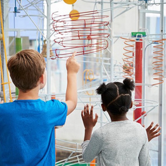 two kids looking at a toy in a science museum
