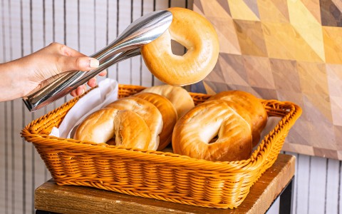 a person holding a bagel in a basket
