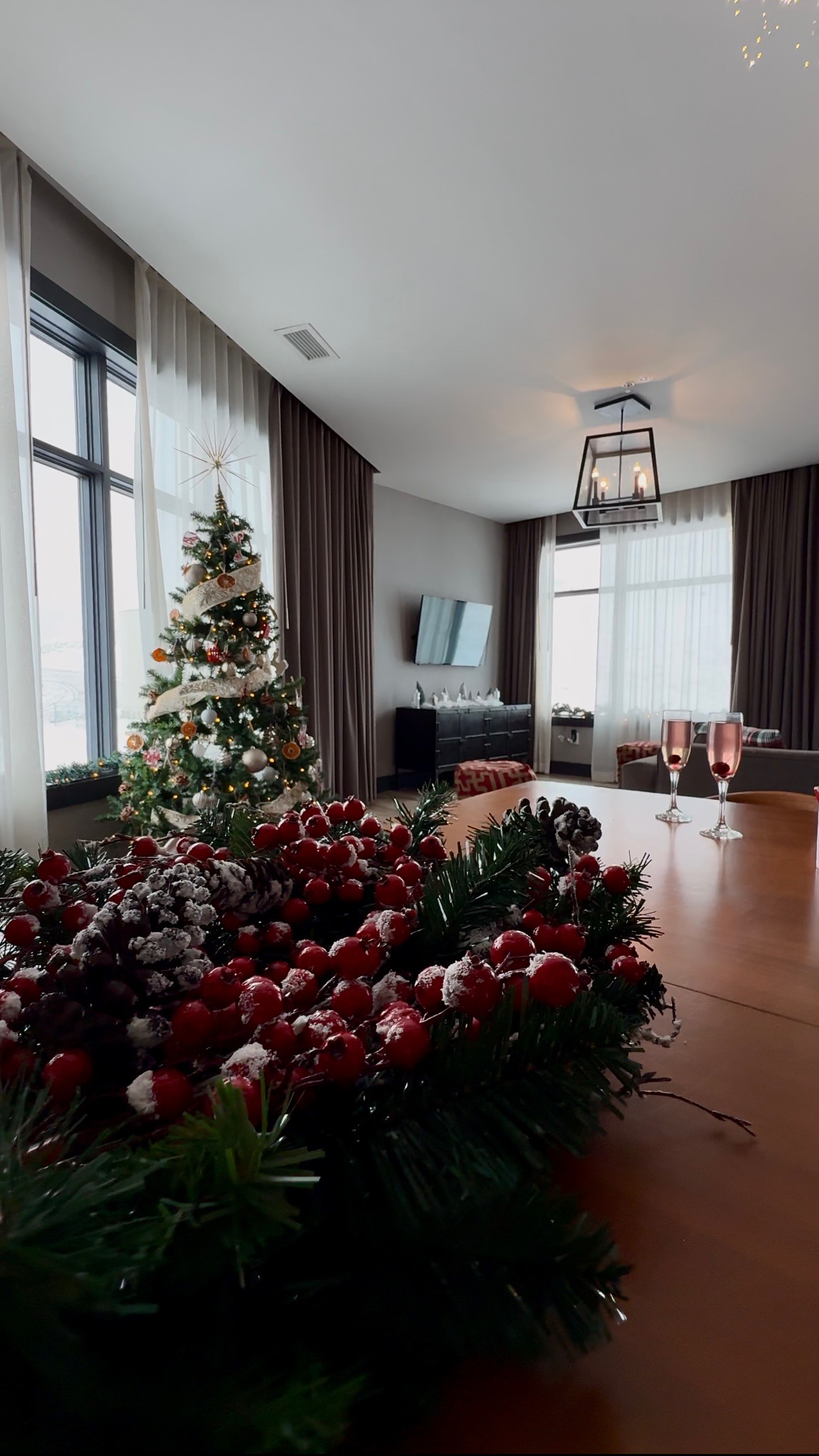 a christmas tree in a room with a table and a glass of wine