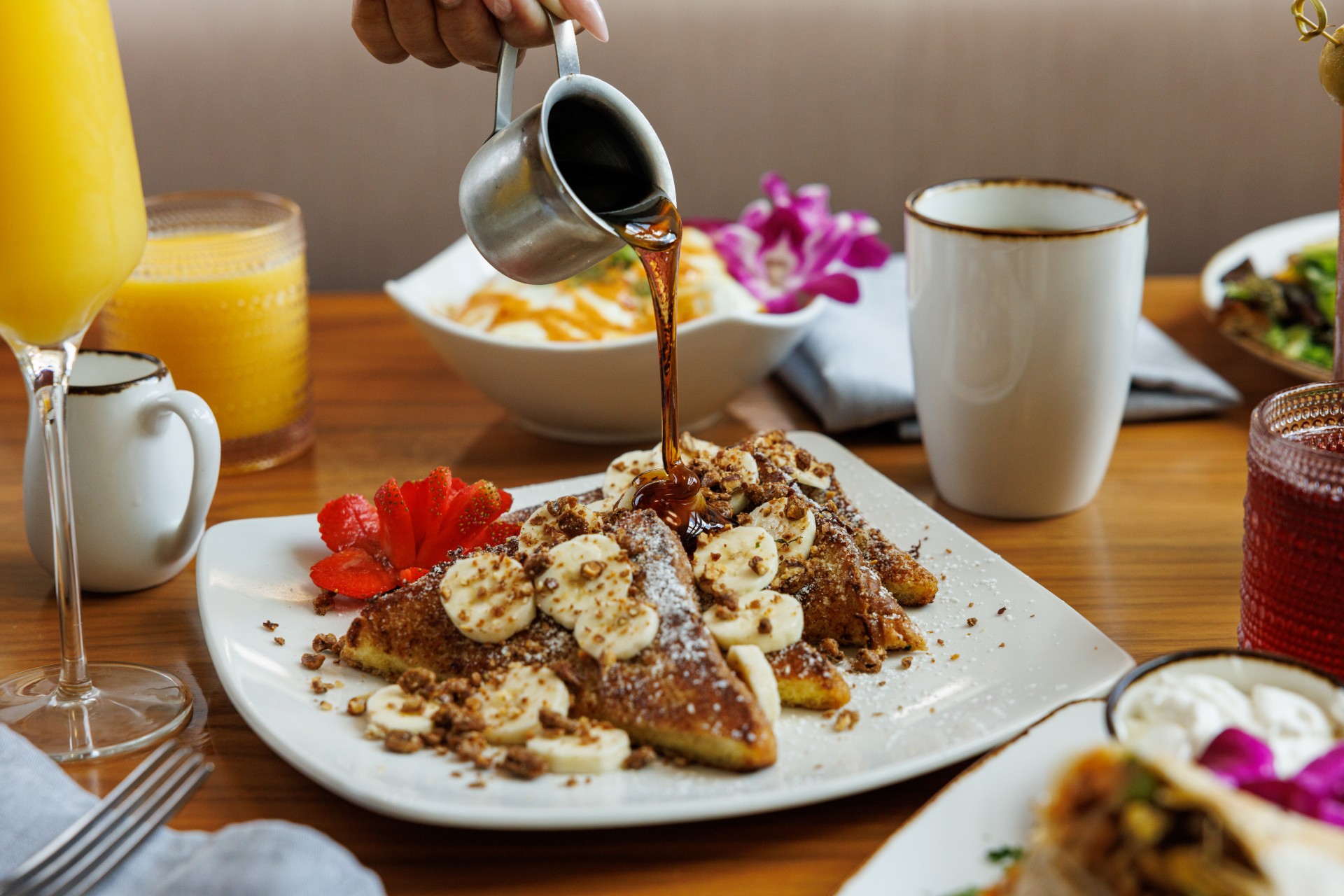 a person pouring syrup on a plate of food