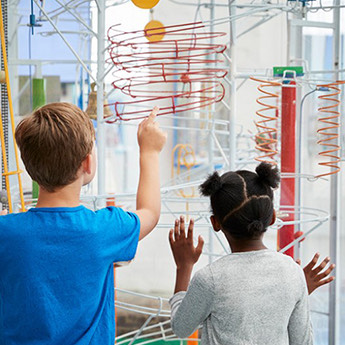 two kids looking at a toy in a science museum