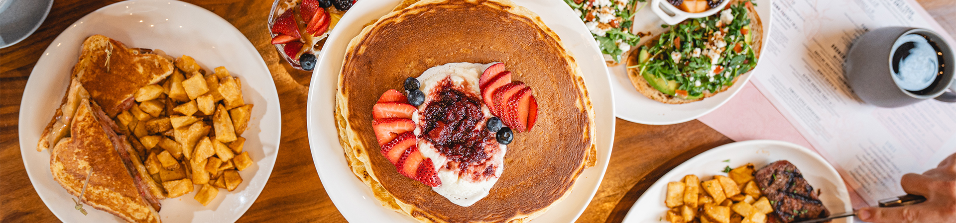 a stack of pancakes with strawberries and cream on top