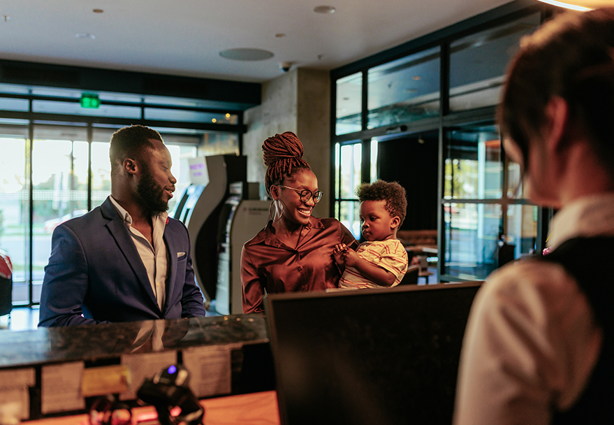a woman holding a baby and a man standing behind a counter