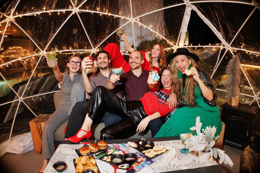 a group of people sitting on a couch in front of a table with food and drinks