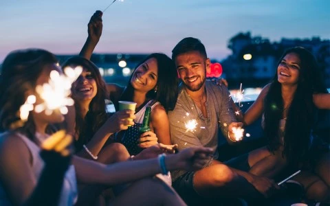 group of friends holding sparklers at night on a rooftop patio