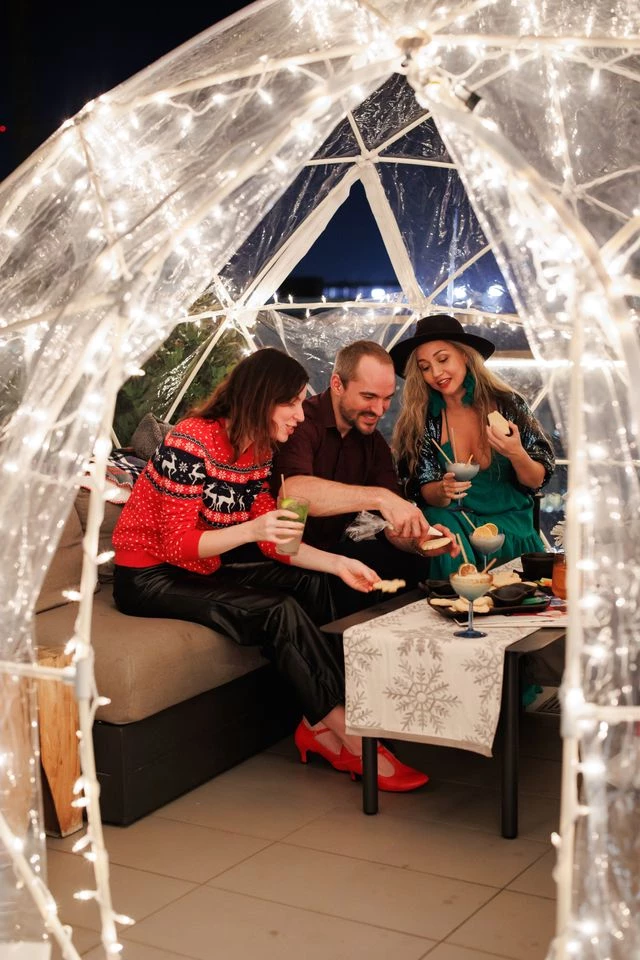 a group of people sitting at a table with food in a tent