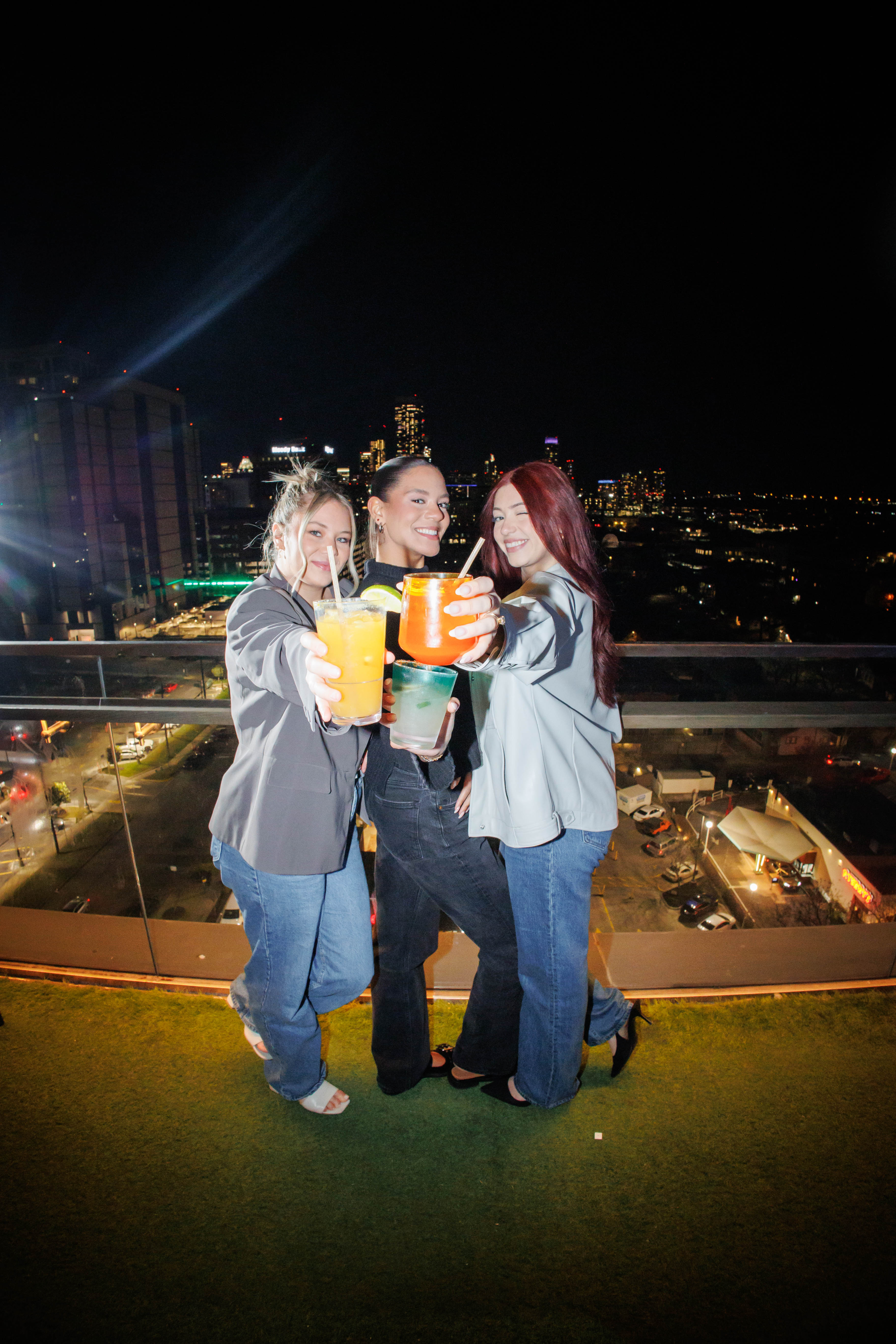 a group of women holding drinks on a balcony
