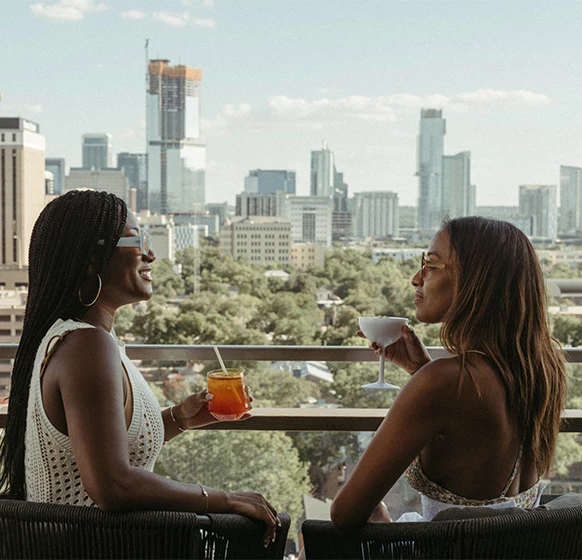 two women sitting on a balcony with drinks