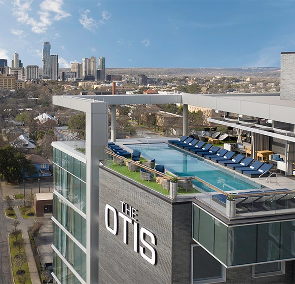 a rooftop pool with chairs and a city in the background