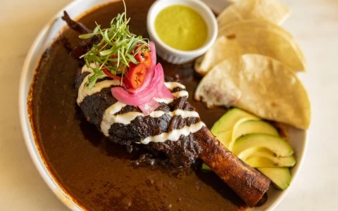 a plate of food with a side of tortilla and sauce