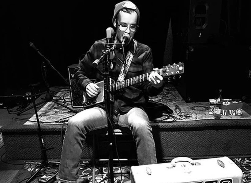 a man playing guitar and singing into microphone