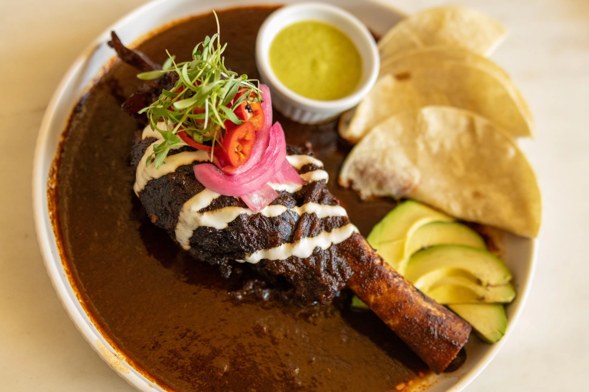 a plate of food with a side of tortilla and sauce