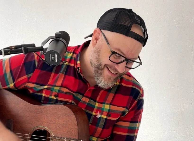 a man with a beard and glasses playing a guitar