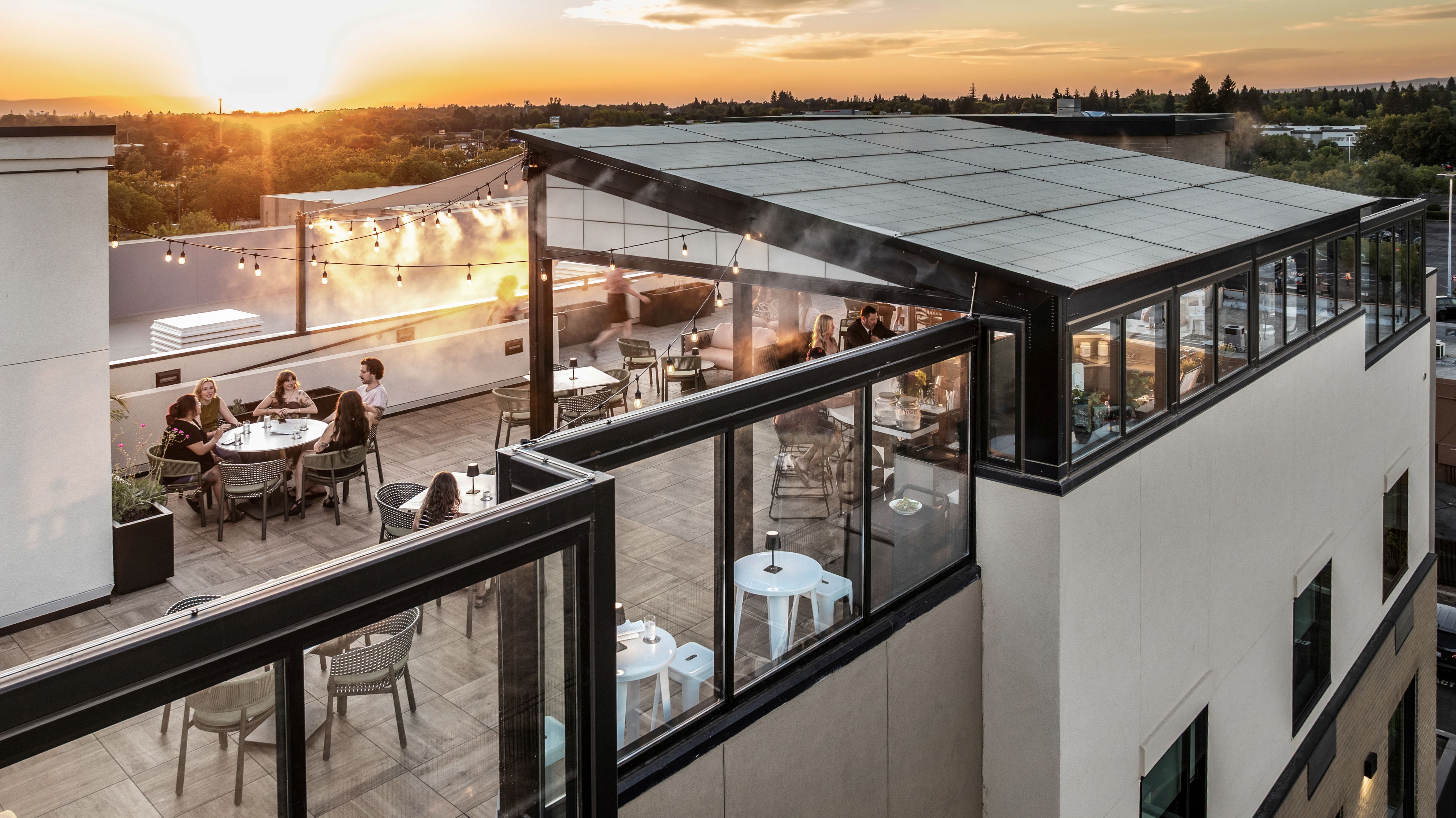 a rooftop patio with people sitting at tables and chairs