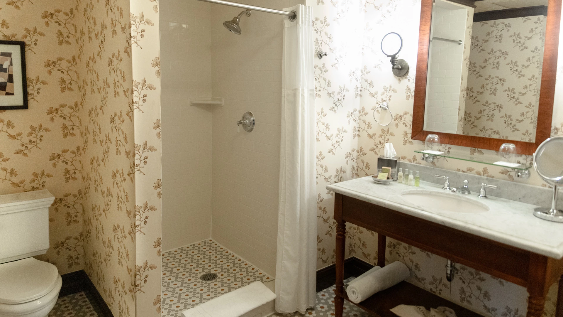 A bathroom with a shower, toilet, vanity, and mirror
