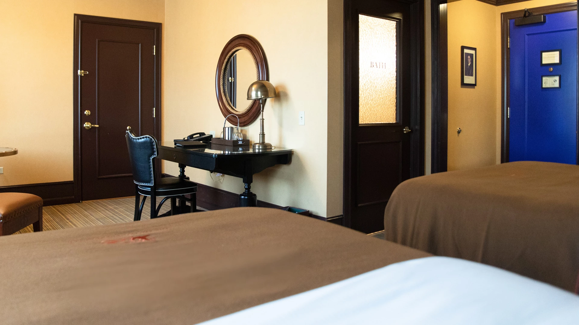 A hotel room with two beds, a desk, and a mirror