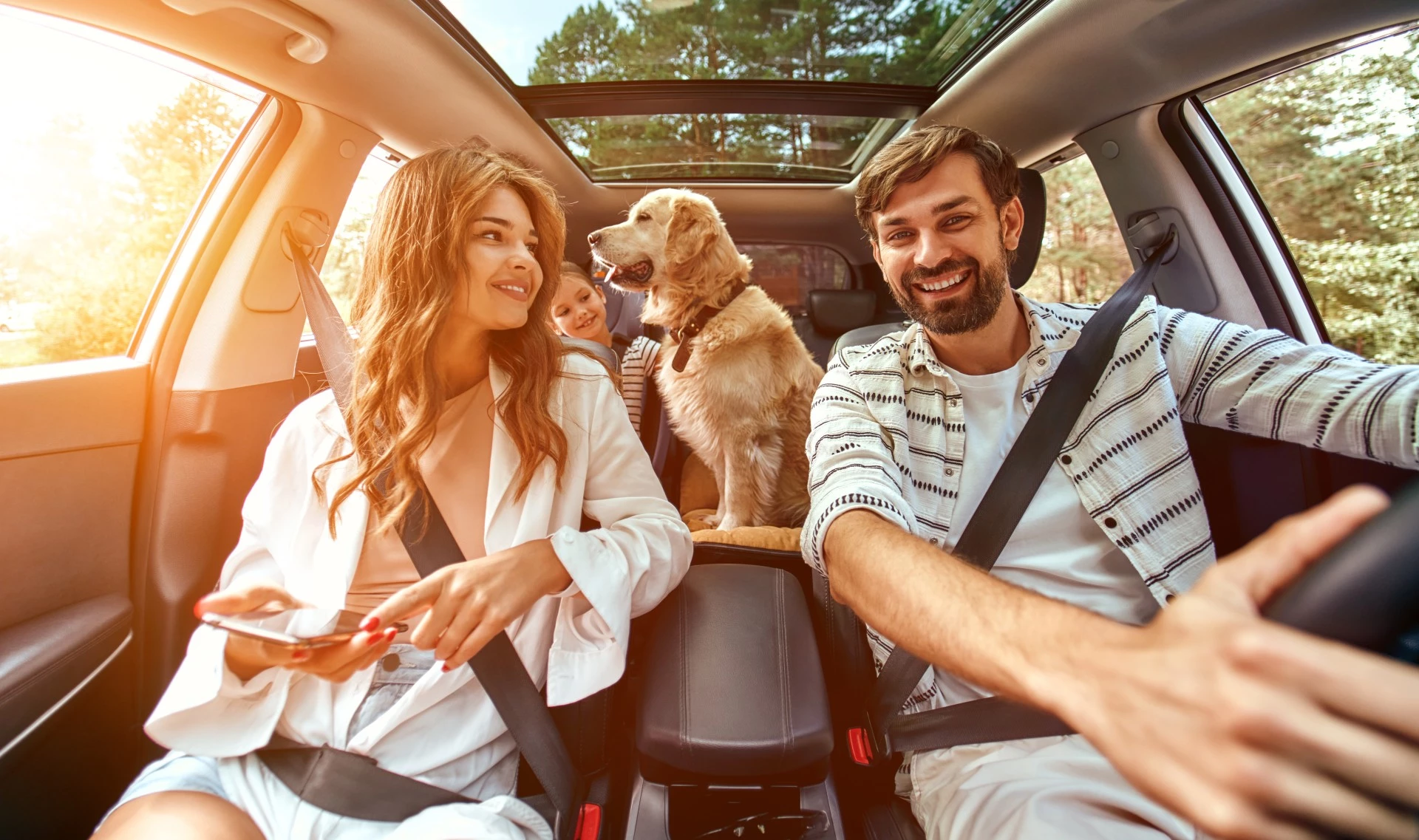 a man and woman in a car with a dog and a child on their way to oxford suites