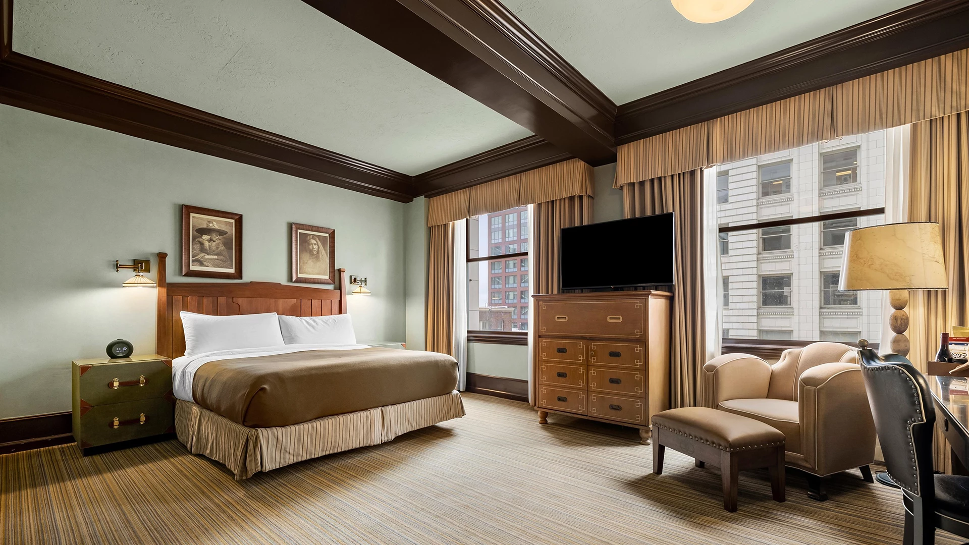 A hotel room with a bed, TV, chair, and window