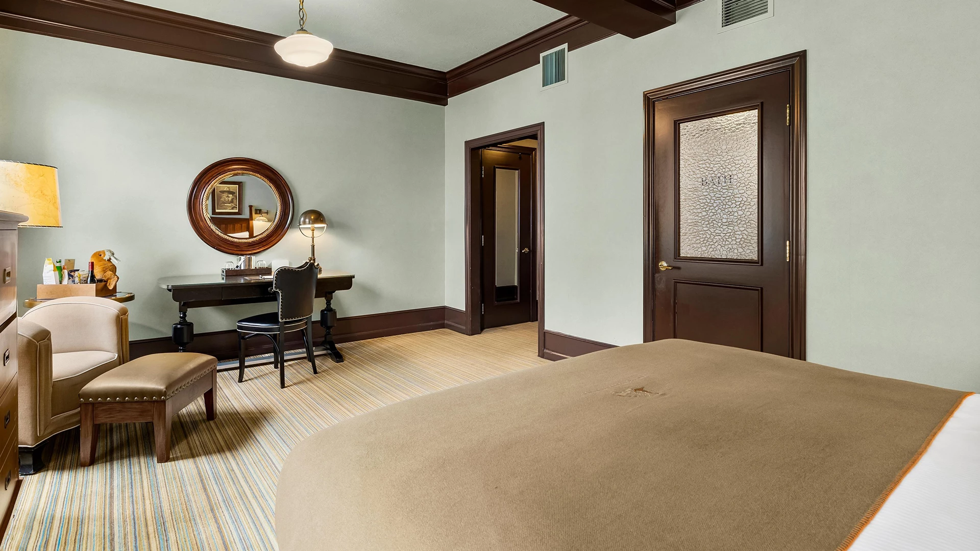 A hotel room with a large bed, desk, and chair.