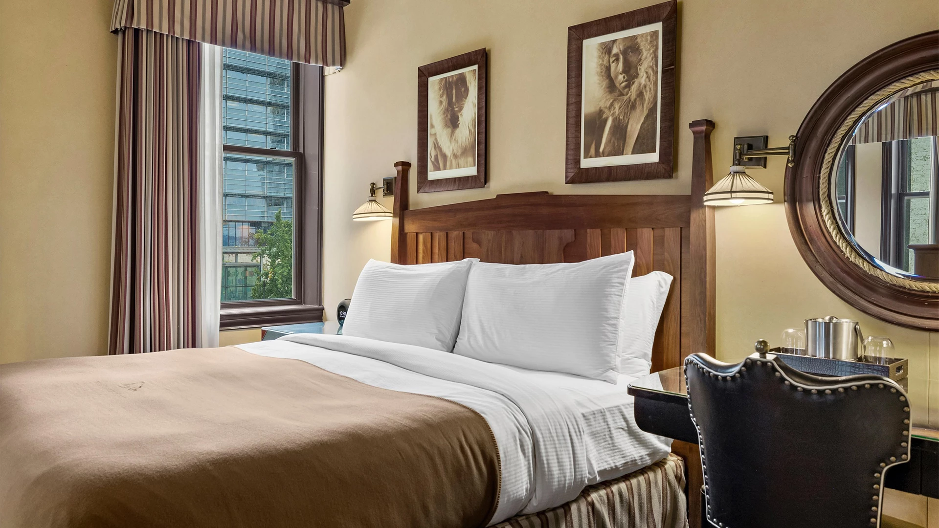A hotel room with a bed, window, mirror, and chair.