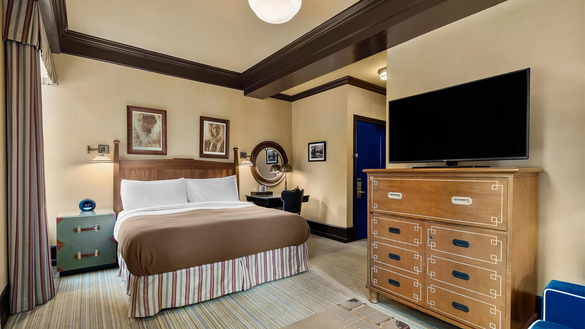 A hotel room with a bed, dresser, TV, and nightstand.