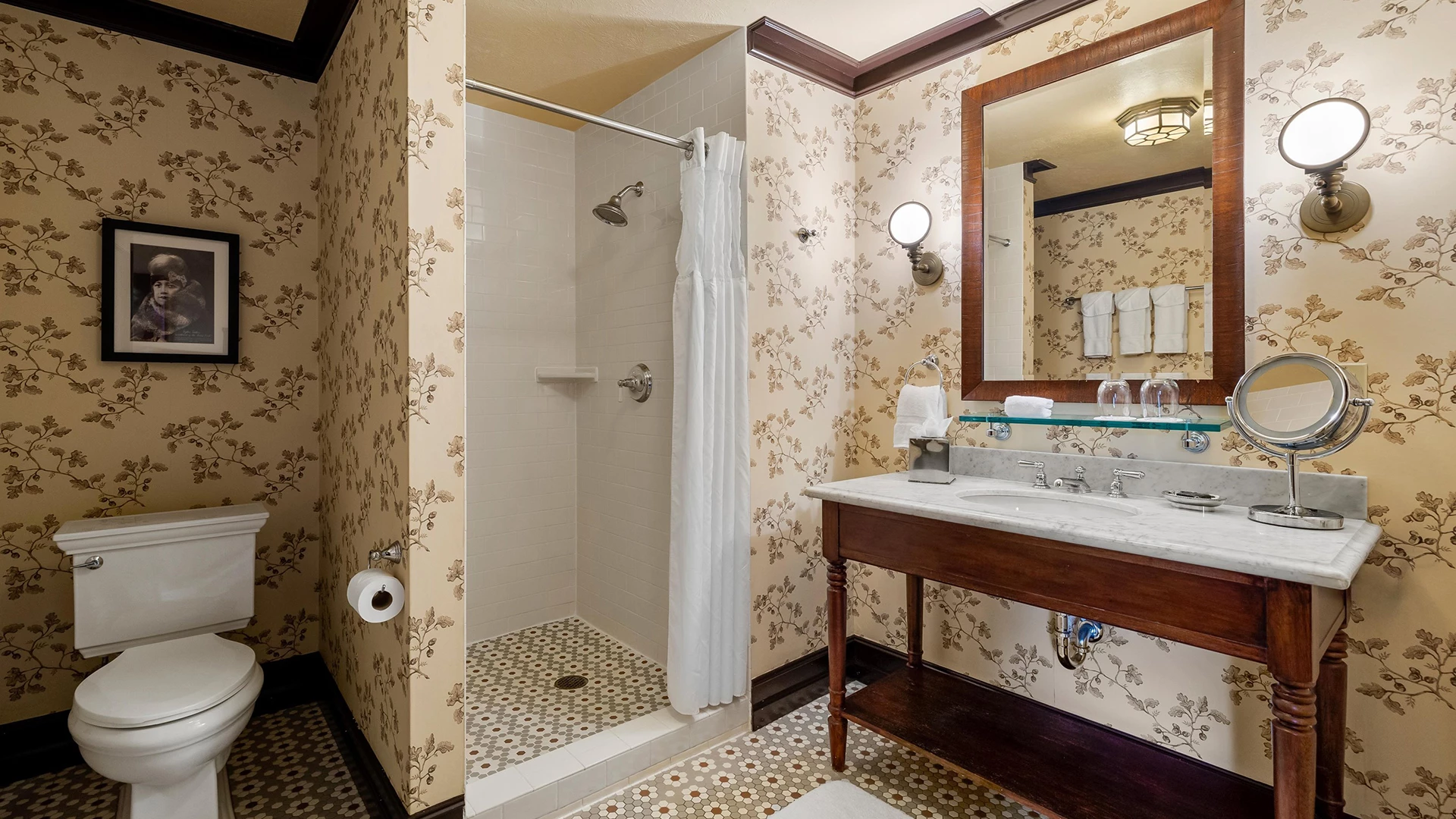 A bathroom with a toilet, shower, sink, and mirror