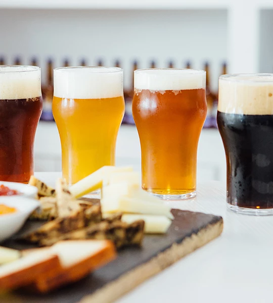 a group of glasses of beer and cheese on a table