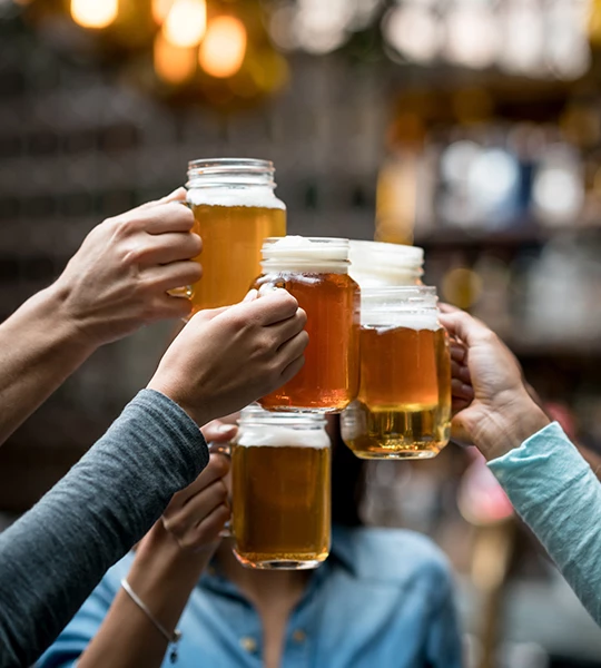 a group of people holding up mugs of beer