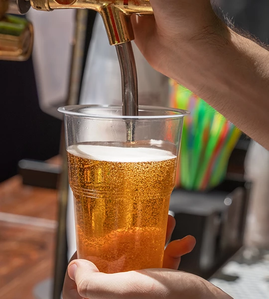 a person pouring a beer into a plastic cup