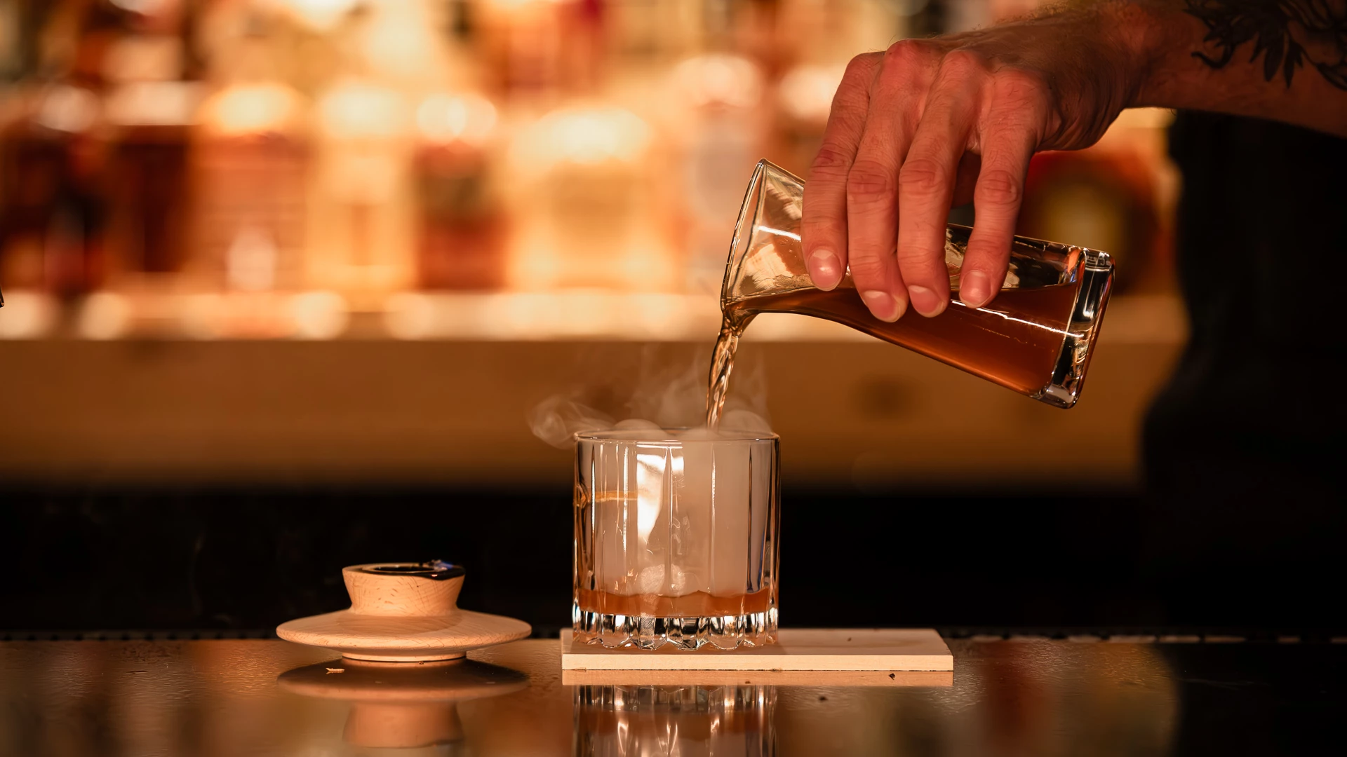 a person pouring a drink into a glass
