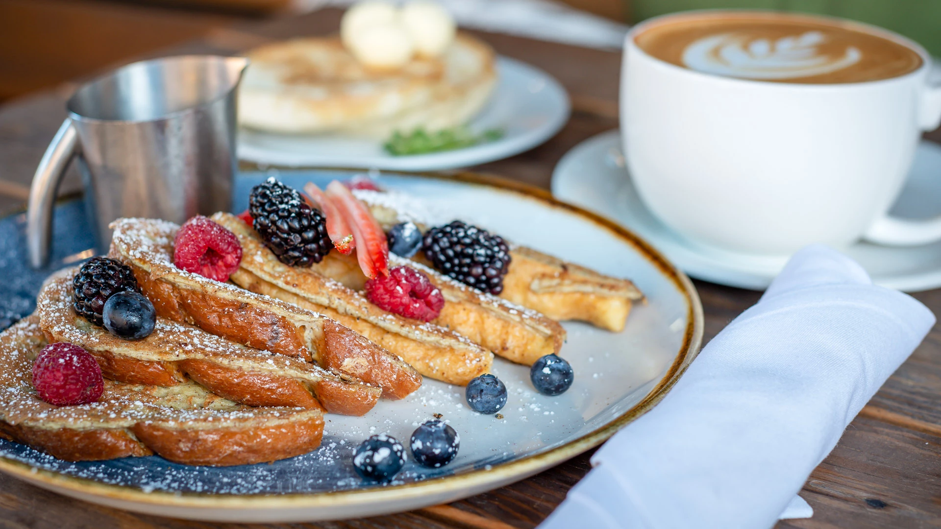 a plate of food with berries and a cup of coffee