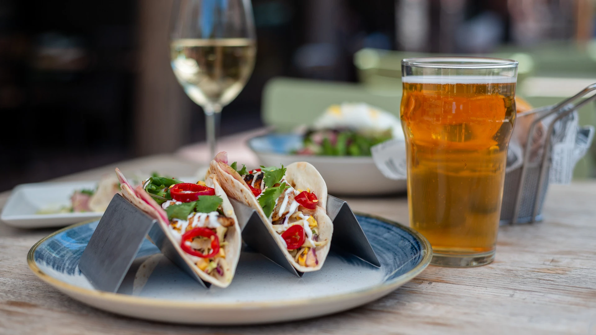 tacos on a plate next to a glass of beer