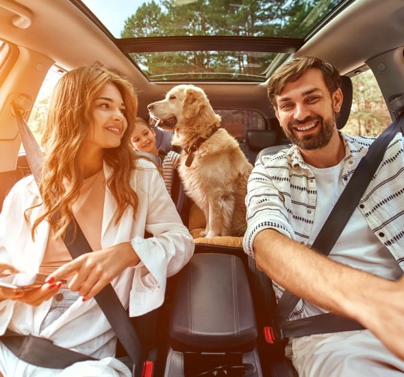 a man and woman in a car with a dog and a child on their way to oxford suites