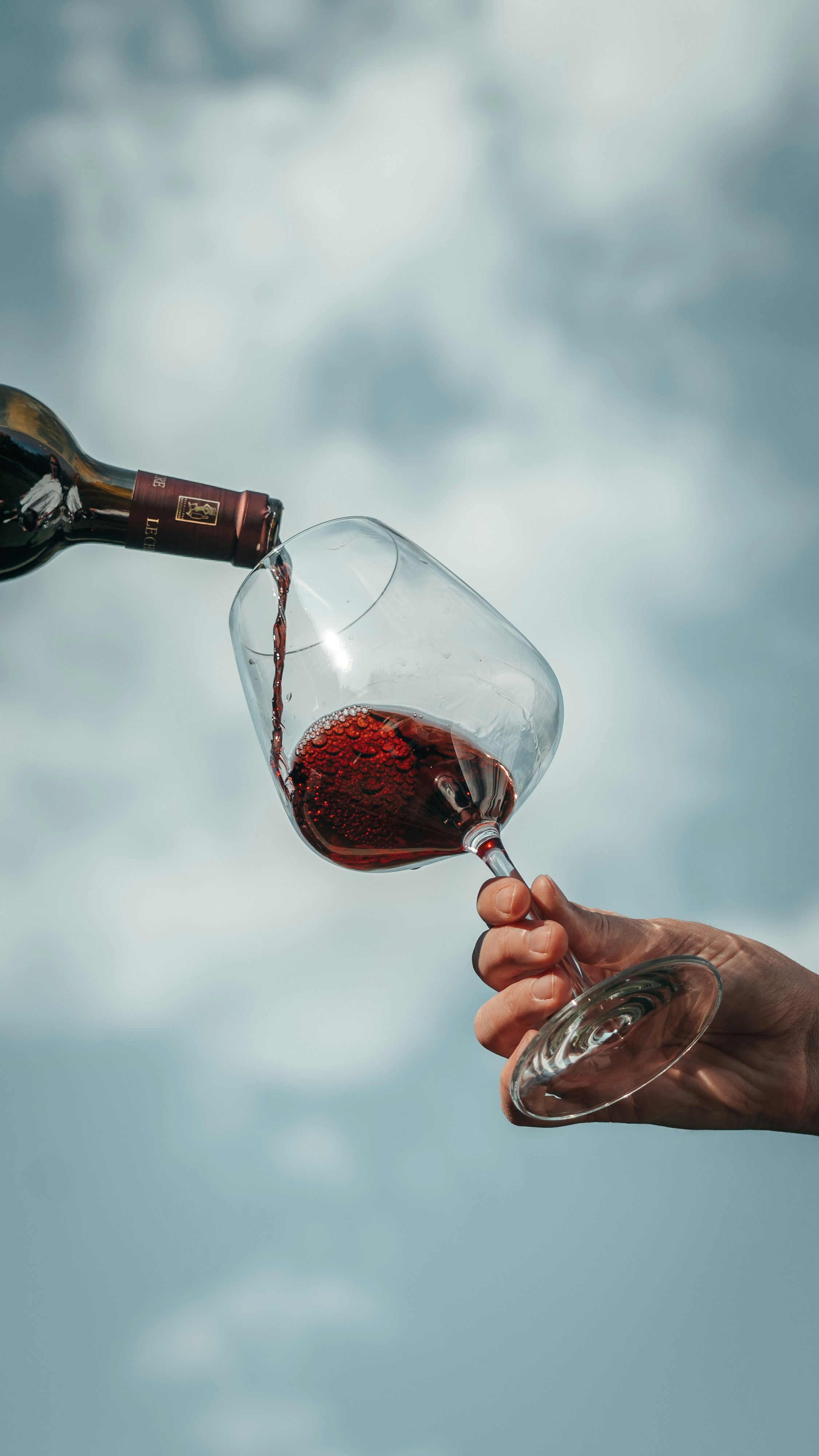 a hand pouring red wine into a glass at Arbor Crest Winery near Oxford Suites Spokane Valley