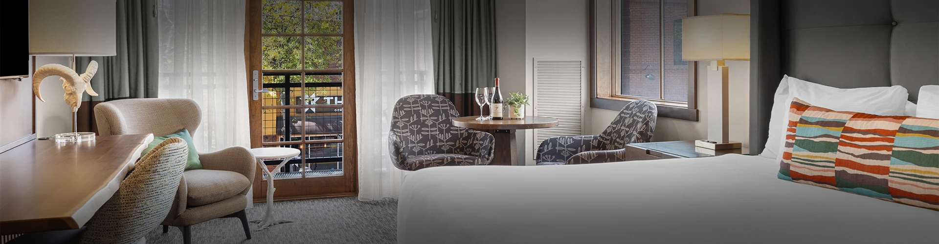 a table with wine bottles and chairs in a hotel room