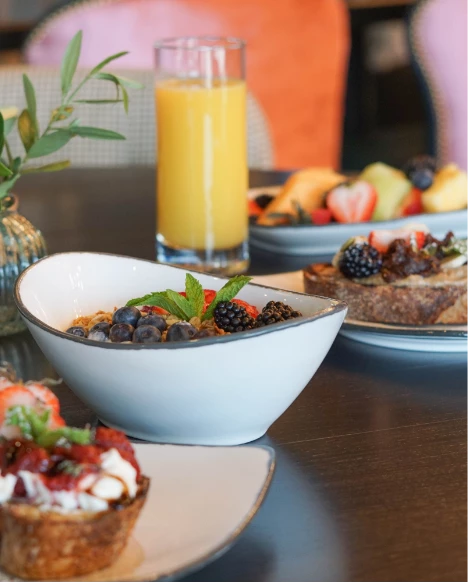 a table with plates of food and a glass of juice