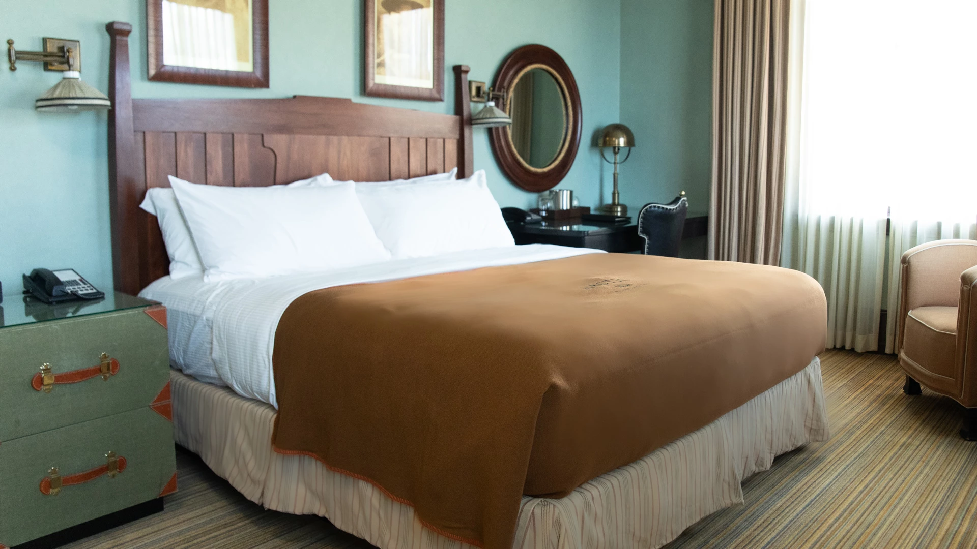 A hotel room with a bed, nightstand, chair, and mirror