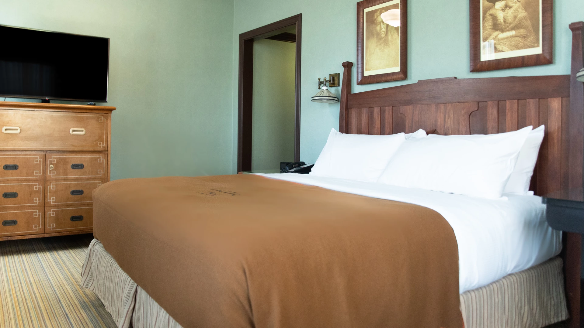 A hotel room with a bed, dresser, and TV.