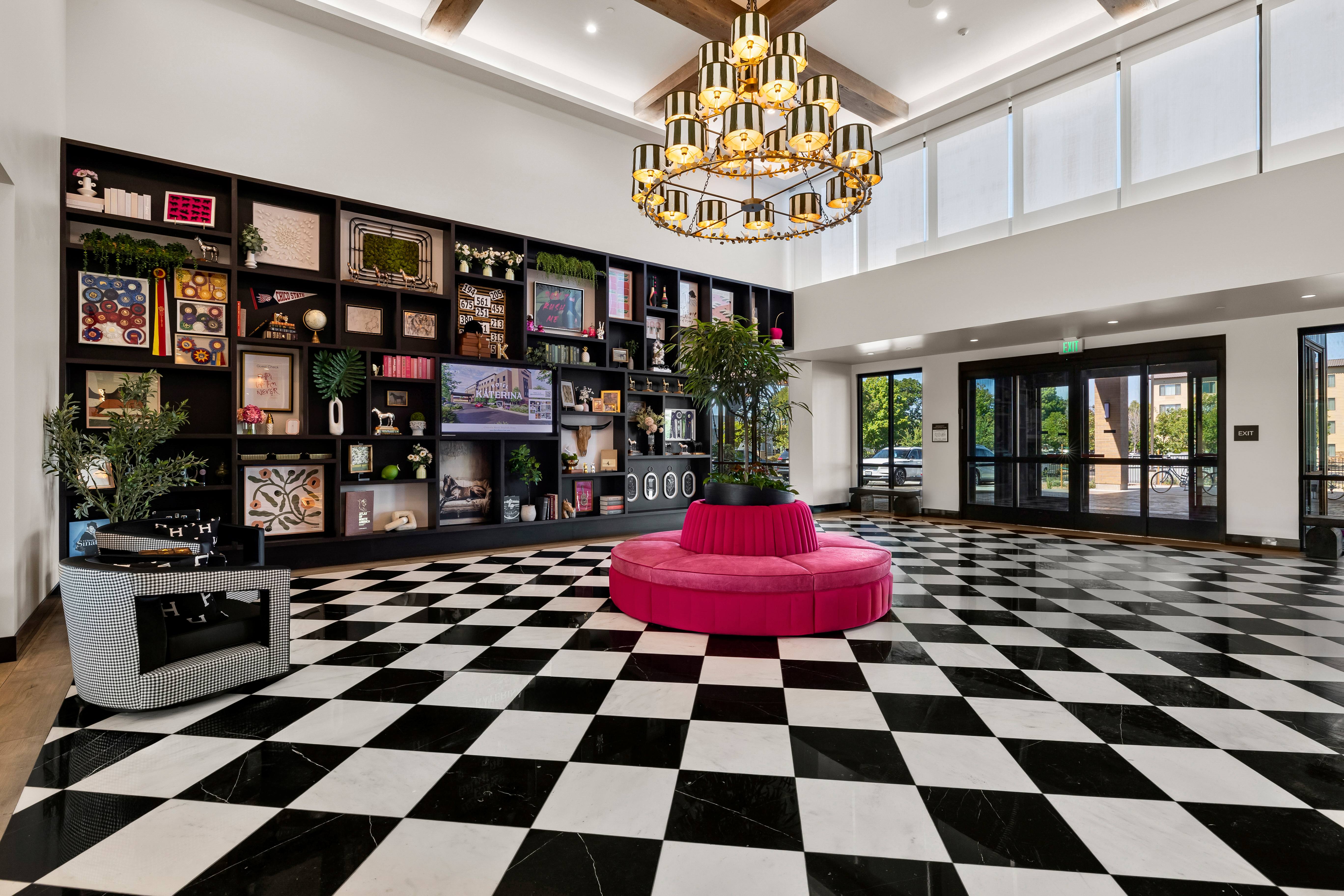 a room with a black and white checkered floor and a pink round bench