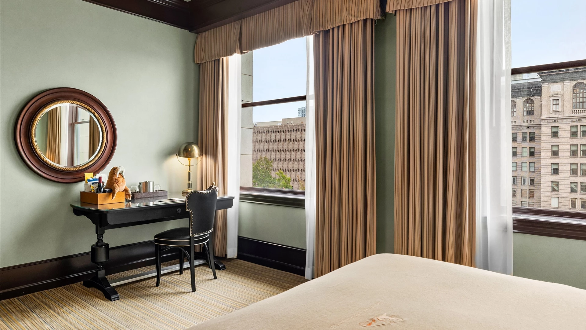 A hotel room with a desk, chair, mirror, and bed
