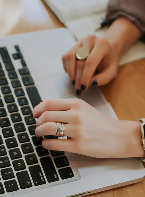 a person's hands with rings on a laptop