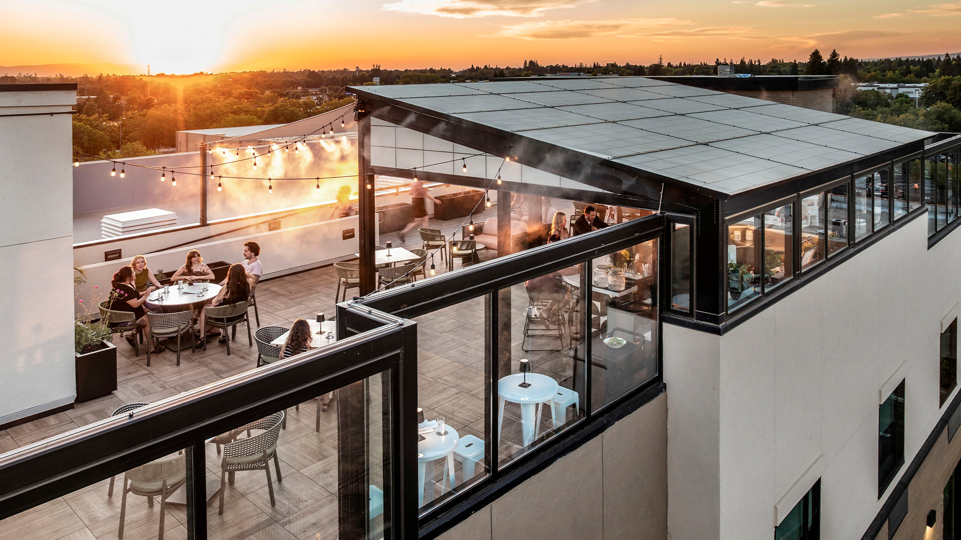 a rooftop patio with people sitting at tables and chairs