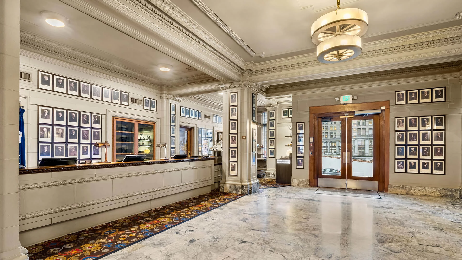 A wide-angle view of a hotel lobby with a reception desk, marble floor, and ornate molding.