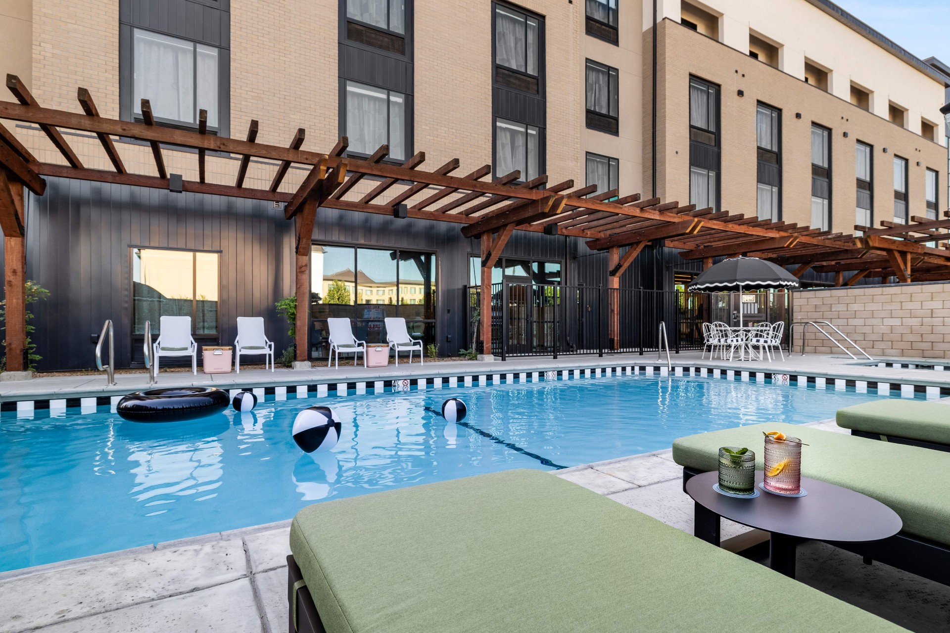 a pool with chairs and umbrellas in front of a building